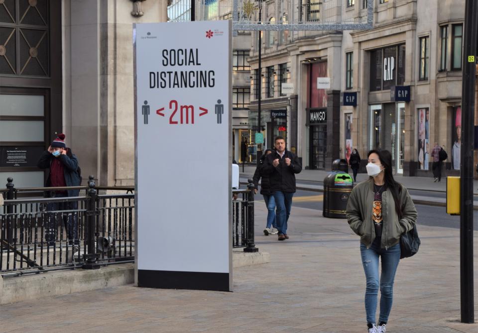  A woman wearing a face mask as a precaution walking past a social distancing sign on Oxford Street. Most shops, restaurants and businesses have closed as the second month-long nationwide Covid 19 lockdown begins in England. (Photo by Vuk Valcic / SOPA Images/Sipa USA) 