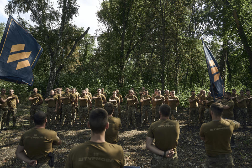 Soldiers of Ukraine's 3rd Separate Assault Brigade shout slogans as they stand in line, near Bakhmut, the site of fierce battles with the Russian forces in the Donetsk region, Ukraine, Sunday, Sept. 3, 2023. (AP Photo/Libkos)