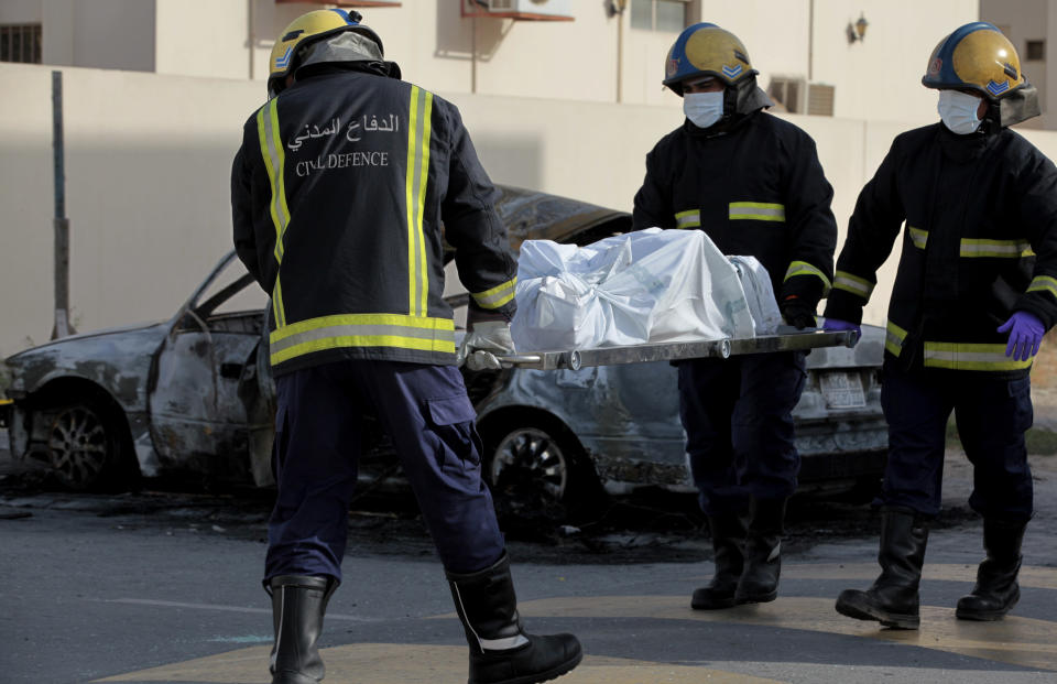 Civil defense workers carry a body removed from a burned-out car to an ambulance in Mughsha, Bahrain, Saturday, April 19, 2014. Authorities in Bahrain say an apparent car bombing has killed two people and wounded one west of the capital, Manama. Bahrain has been roiled by three years of unrest, with a Shiite-dominated opposition movement demanding greater political rights from the Sunni monarchy. (AP Photo/Hasan Jamali)