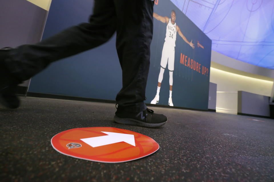 A passer-by walks near a safe-distancing pedestrian traffic marker attached to a floor at the Naismith Memorial Basketball Hall of Fame, in Springfield, Mass., Tuesday, June 23, 2020. The museum is scheduled to reopen in the beginning of July 2020 with a whole new look after a $22 million renovation. (AP Photo/Steven Senne)