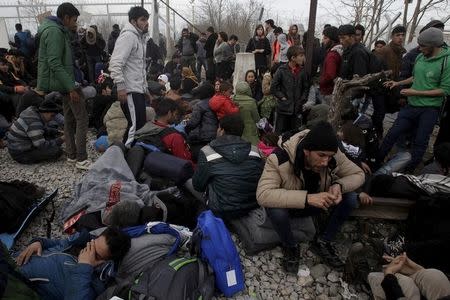 Refugees and migrants rest next to a border fence at the Greek-Macedonian border, following a demand by Macedonia for additional identification from people seeking to cross the border and head to Western Europe, near the village of Idomeni, Greece, February 22, 2016. REUTERS/Alexandros Avramidis