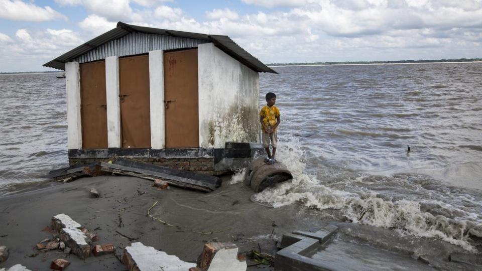 Un niño que perdió sus pertenencias por la erosión del río se refugia en un refugio que ahora está nuevamente erosionado.