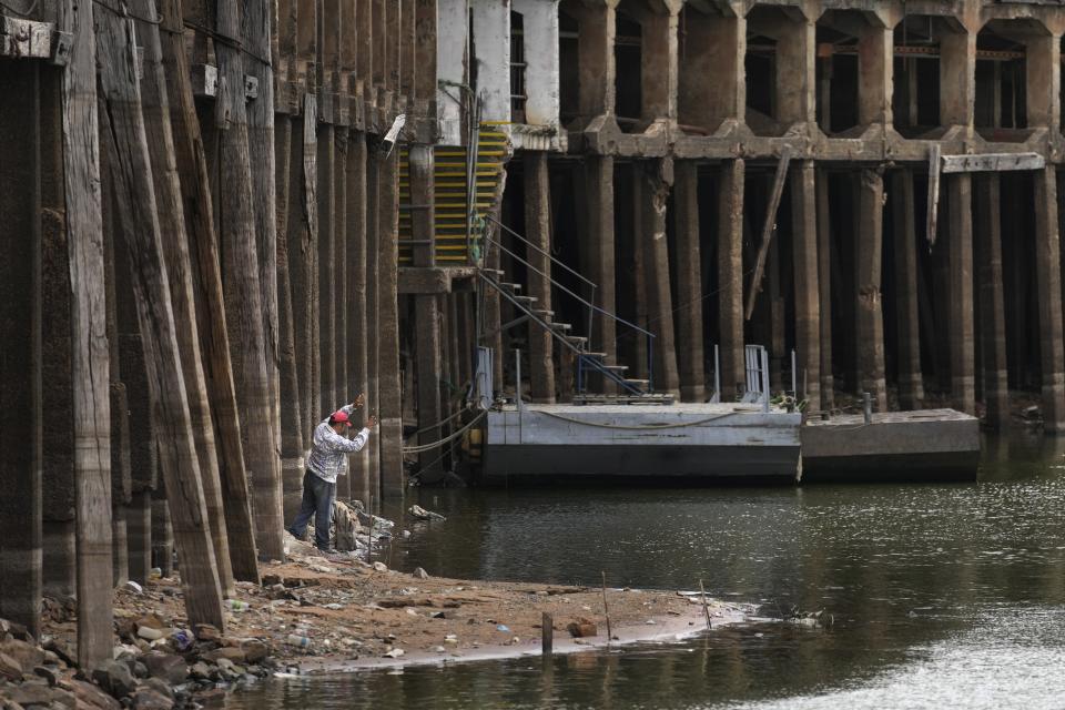 A man fishes down on the exposed support beams of the port of Asuncion amid a historic drought that is affecting the river's level, in Paraguay, Tuesday, Sept. 21, 2021. (AP Photo/Jorge Saenz)