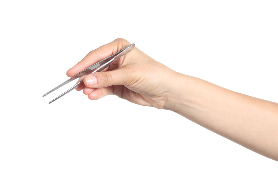 Woman hand using a small tweezers isolated on a white background