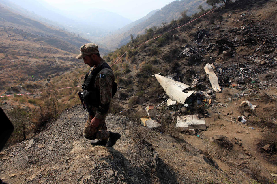 A Pakistani soldier walks near the wreckage of a PIA plane