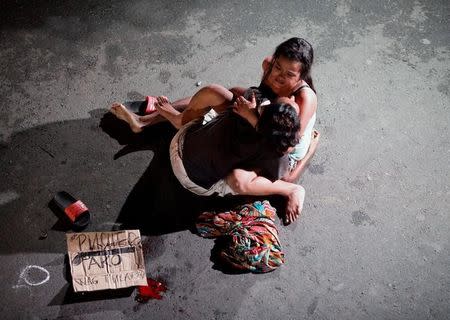 Jennelyn Olaires, 26, cradles the body of her partner, who was killed on a street by a vigilante group, according to police, in a spate of drug related killings in Pasay city, Metro Manila, Philippines July 23, 2016. A sign on a cardboard found near the body reads: "Pusher Ako", which translates to "I am a drug pusher." REUTERS/Czar Dancel