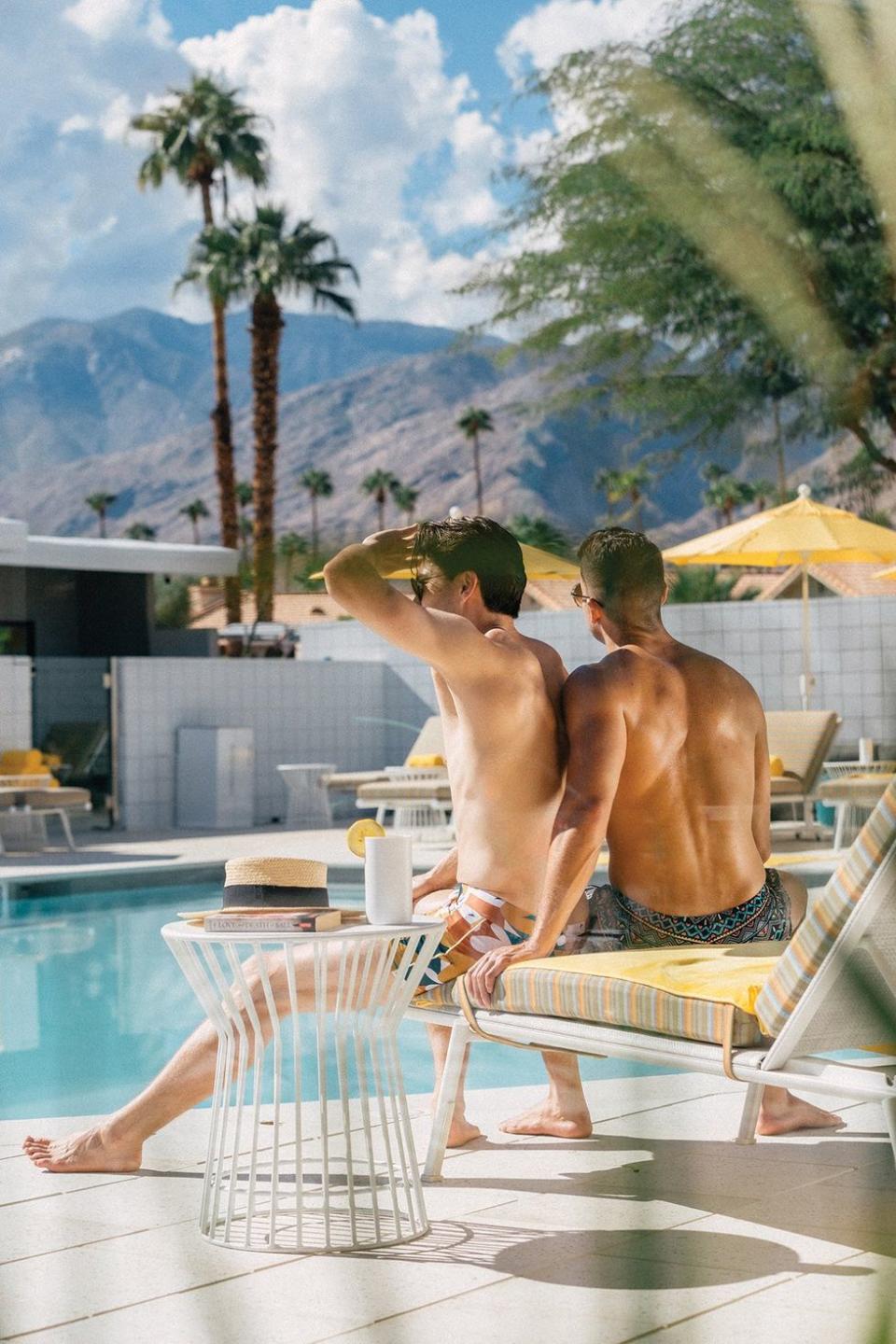 A gay couple lounge poolside at the Twin Palms Resort, a gay men's clothing optional resort in Palm Springs