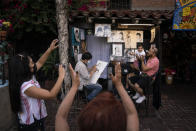 Relatives of 1-year-old Janelly Cerda, visiting from Tijuana, Mexico, gesture to make the toddler smile for photos as caricaturist Hernan Davila sketches the family on Olvera Street in Los Angeles, Tuesday, June 8, 2021. Most businesses are no longer open daily and many have cut back to four or five days, said Valerie Hanley, treasurer of the Olvera Street Merchants Association Foundation and a shop owner. "We're not like a local restaurant in your town," Hanley said. "We're one of those little niche things. If you can't fill the niche with the right people, we're in trouble." (AP Photo/Jae C. Hong)