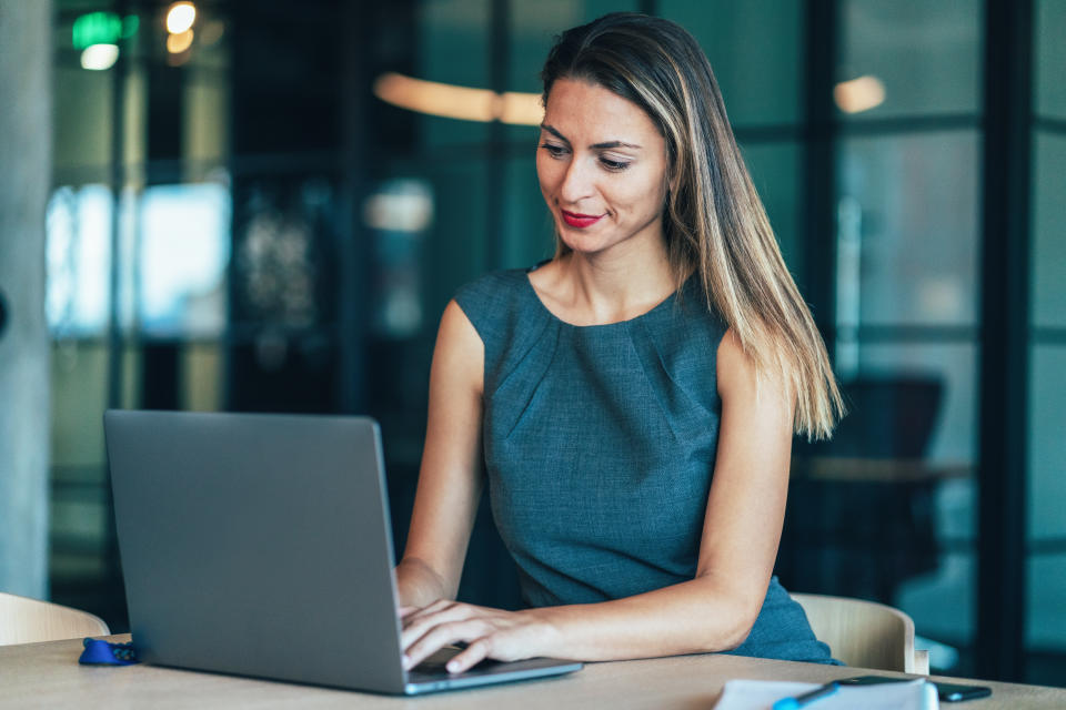 Portrait of young and beautiful business woman working at the office using laptop