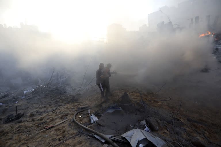 Bomberos palestinos tratan de extinguir un incendio en un edificio destrozado tras un ataque aéreo israelí en la ciudad de Gaza, el miércoles 25 de octubre de 2023