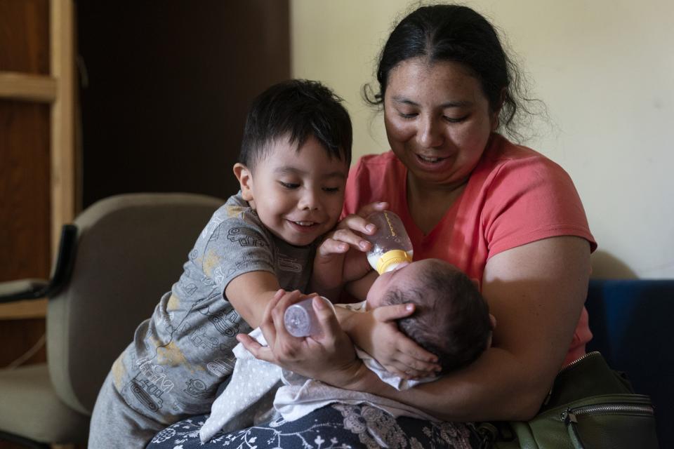 With her son Jaasiel Galvaz, 2, helping hold his brother's head, Yury Navas, 29, of Laurel, Md., feeds her two-month-old baby, Ismael Galvaz, with the only formula he can take without digestive issues, Enfamil Infant, from her dwindling supply of formula at their apartment in Laurel, Md., Monday, May 23, 2022. After this day's feedings she will be down to their last 12.5 ounce container of formula. Navas doesn't know why her breastmilk didn't come in for her third baby and has tried many brands of formula before finding the one kind that he could tolerate well, which she now says is practically impossible for her to find. To stretch her last can she will sometimes give the baby the water from cooking rice to sate his hunger. (AP Photo/Jacquelyn Martin)