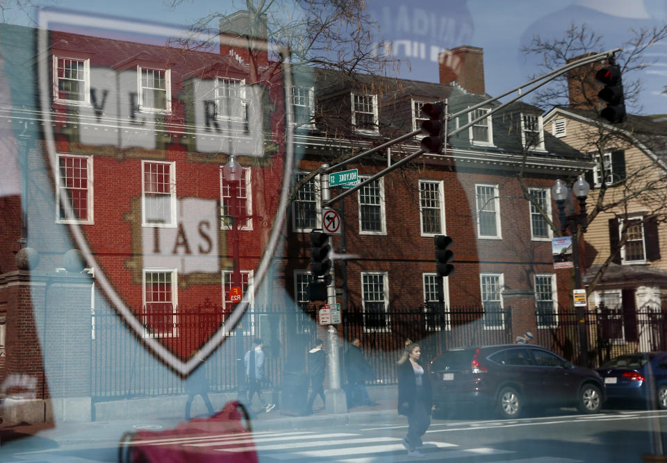 CAMBRIDGE, MA - MARCH 11:  Pedestrians are reflected in a window of a store selling Harvard paraphernalia in Cambridge, MA on March 11, 2020. A day after Harvard announced it would be sending students home for the rest of the semester due to coronavirus concerns, Harvard Square was unusually quiet.  (Photo by Jessica Rinaldi/The Boston Globe via Getty Images)