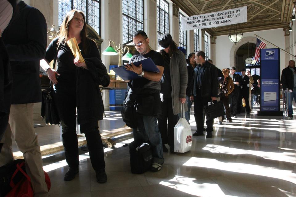 FILE - In this April, 15, 2008, file photo, Jackie Doyle, of Greenwood Lake, N.Y., second from left, waits in line to mail her husband's taxes at the James A. Farley Main Post Office in New York. The package of tax increases and spending cuts known as the “fiscal cliff” takes effect on January 1, 2013, unless Congress passes a budget deal by then. The economy would be hit so hard that it would likely sink into recession in the first half of 2013, economists say. (AP Photo/Tina Fineberg, File)