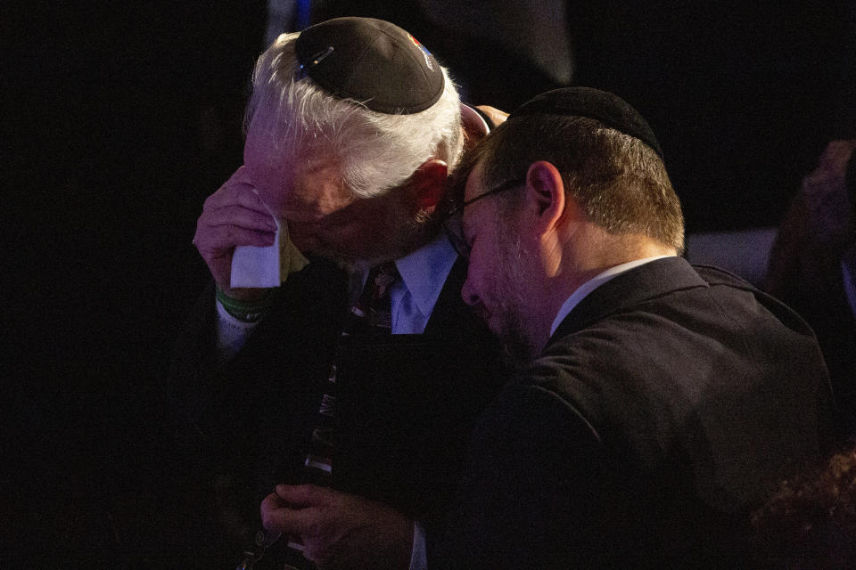 Rabbi Jeffrey Myers, center, of the Tree of Life/Or L'Simcha Congregation, is comforted after saying a prayer for the souls of the deceased during the one-year commemoration of the Tree of Life synagogue attack, at Soldiers & Sailors Memorial Hall and Museum, Sunday, Oct. 27, 2019, in Pittsburgh. (AP Photo/Rebecca Droke)