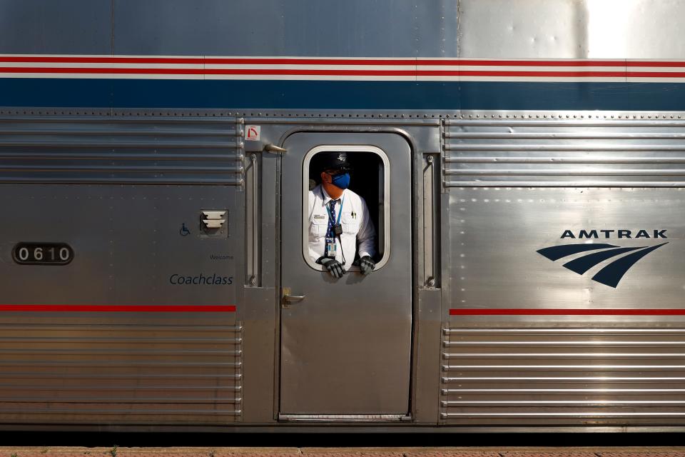 An Amtrak conductor wearing a protective mask looks down the train platform at the Galesburg, Ill., station Tuesday, June 15, 2021, in Galesburg.