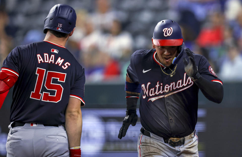 Washington Nationals' Ildemaro Vargas, right, runs to the dugout past Riley Adams (15) after Vargas scored on a single by Alex Call during the second inning of a baseball game against the Texas Rangers in Arlington, Texas, Wednesday, May 1, 2024. (AP Photo/Gareth Patterson)