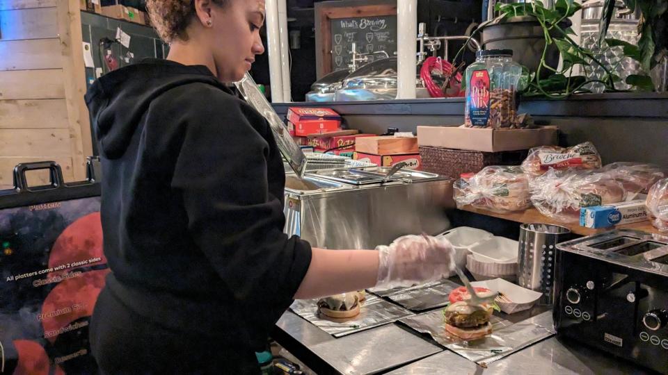 Southern Perfection BBQ co-owner Joanna Glover adding the cabernet cheese sauce to burger Jan. 25, 2024.