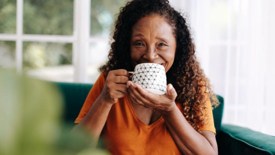 mature woman sipping tea outside while smiling