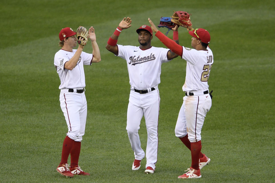 De izquierda a derecha, los jardineros de los Nacionales de Washington, Andrew Stevenson, Víctor Robles y Juan Soto, festejan tras derrotar a los Mets de Nueva York en el primer juego de una doble cartelera, el sábado 26 de septiembre de 2020 (AP Foto/Nick Wass)