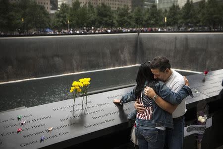 Eileen Esquilin hugs her husband Joe Irizarry while mourning the loss of her brother Ruben Esquilin Jr during memorial observances held at the site of the World Trade Center in New York, September 11, 2014. REUTERS/Andrew Burton/POOL