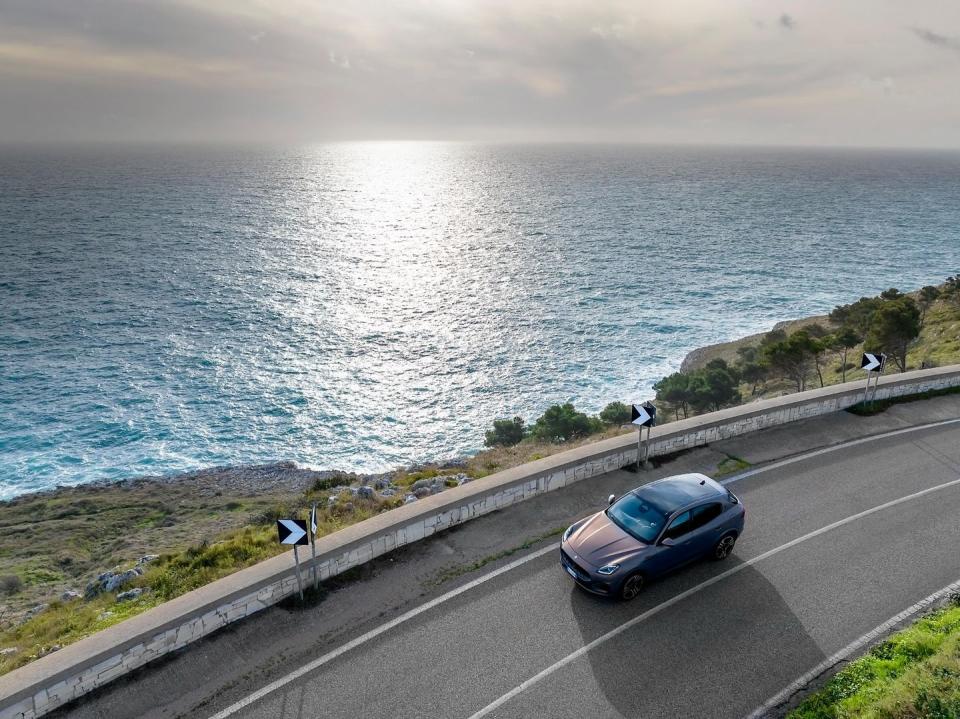 a car driving on a road by a body of water