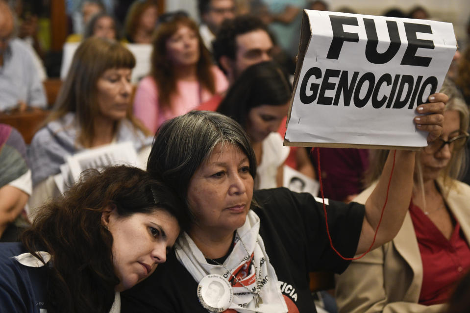 A person holds up a sign with a message that reads in Spanish: "It was genocide," in a courtroom where activists and the relatives of victims listen to the verdict for former police officers on trial for crimes against humanity during the 1976-1983 dictatorship, in La Plata, Argentina, Tuesday, March 26, 2024. The officers were convicted on Tuesday of torturing over 20 pregnant women and stealing at least 10 babies, seven of which have been identified and recovered. Hundreds of babies were abducted during the Argentine dictatorship. (AP Photo/Gustavo Garello)