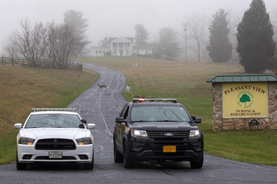 A deer crosses through the fog as a Carroll County Sheriff officer and a Maryland State Trooper guard the driveway to the Pleasant View Nursing Home, in Mount Airy, Md., Sunday, March 29, 2020. Maryland's governor said Saturday night that the nursing home had been struck by an outbreak of COVID-19. (AP Photo/Jacquelyn Martin)