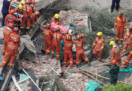 Firefighters carry a casualty on a stretcher at the site where a building collapsed, in Shanghai, China May 16, 2019. REUTERS/Aly Song