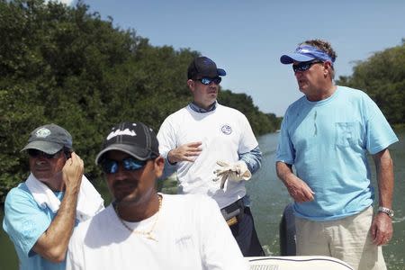 U.S. artist and conservationist Guy Harvey (R) leads a group of volunteers along the San Juan estuary system for the second "mega cleanup" of garbage from the waterway, in San Juan, in this October 26, 2013 file picture. REUTERS/Alvin Baez/Files