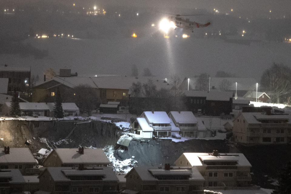 A rescue helicopter files over the site of a landslide in Ask, northeast of Oslo, early Thursday morning Dec. 31, 2020. A landslide smashed into a residential area near the Norwegian capital Wednesday. (Terje Bendiksby/NTB via AP)