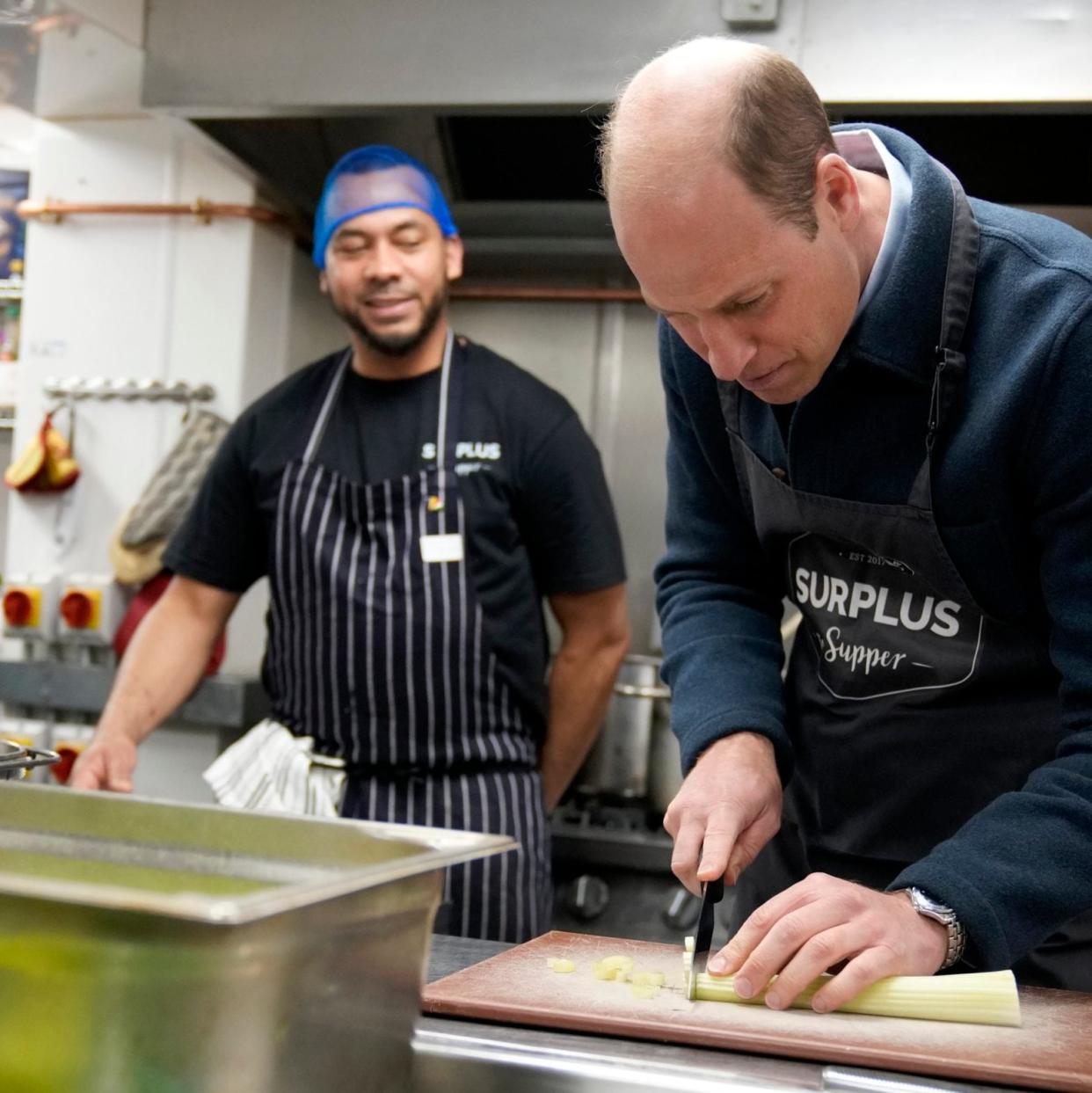 Britain's Prince William cuts celery as he helps to make a bolognase sauce during the visit