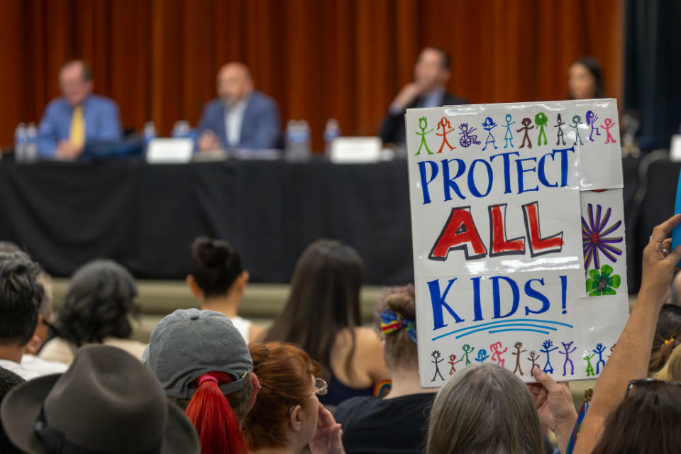 A person holds a sign that says ‘Protect All Kids’ during a meeting of the Chino Valley school board.
