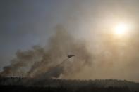 An aircraft drops water over a fire in Varibobi area, northern Athens, Greece, Wednesday, Aug. 4, 2021. Firefighting planes were resuming operation at first light Wednesday to tackle a major forest fire on the northern outskirts of Athens which raced into residential areas the previous day, forcing thousands to flee their homes amid Greece's worst heatwave in decades. (AP Photo/Thanassis Stavrakis)