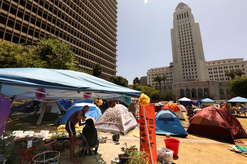 LOS ANGELES, CA - AUGUST 03, 2020 - - Randalee, left, braids the hair of a fellow camper at the Black Unity LA encampment across the street from City Hall in Grand Park on August 3, 2020. The encampment is in support of Black Lives Matter and has been there since late May. There are a couple of dozen people living here and is made up of activists and protesters. The camp has a community garden and a tent which carries food, antibacterial cream and other items to ward off coronavirus. (Genaro Molina / Los Angeles Times) FYI Editor: Randalee only wanted her first name used.