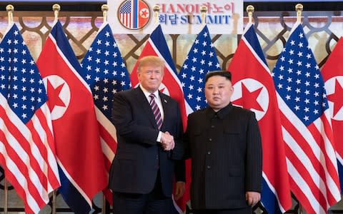 Donald Trump and Kim Jong-un shake hands in front of the US and North Korean flags at the Hanoi Summit earlier this year - Credit: White House Photo/Shealah Craighead/Handout