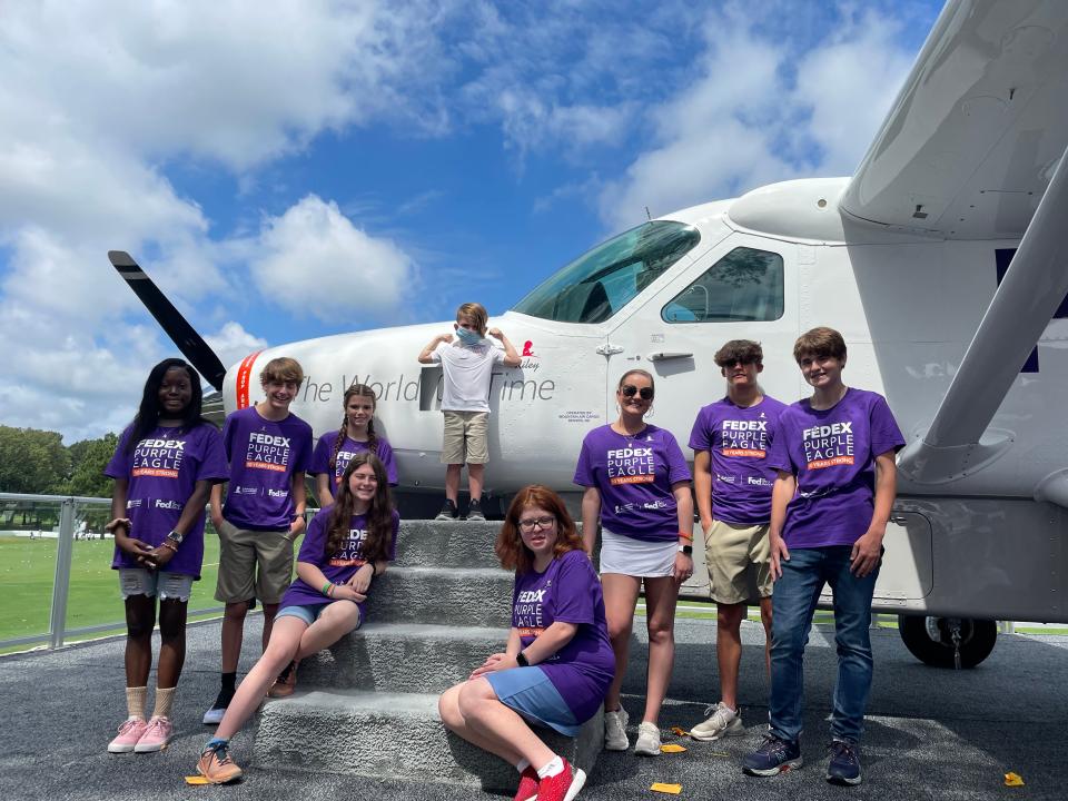Nine of the 10 St. Jude patients who have had FedEx planes named after them as part of the Purple Eagle program, including Allie Allen (wearing sunglasses), pose for a photo with 2022 honoree, Riley.