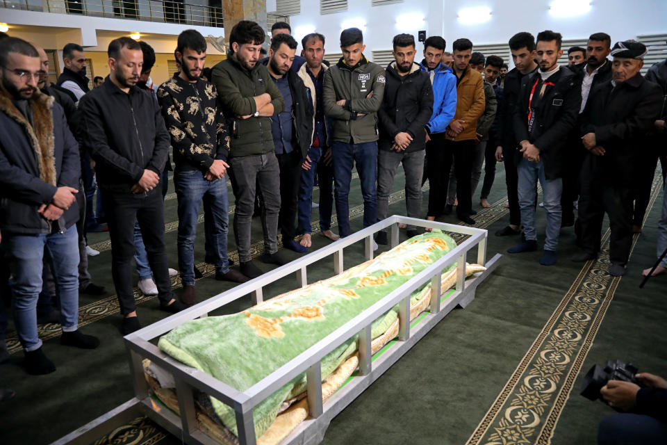 Mourners pray by the coffin of Gaylan Delir Ismael, 25, from Iraq's Kurdish region, at his funeral at a mosque in Irbil, Iraq, early Monday, Nov. 15, 2021. Like thousands of other Iraqis and Syrians, Gaylan had traveled to Belarus on an easily obtained tourist visa in the hope of getting to Germany and starting a new life. But he never made it there, dying in a dark and soggy forest on the Belarus-Poland border. (AP Photo)