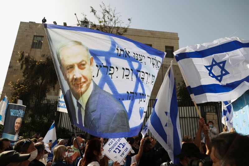 Supporters of Israeli Prime Minister Benjamin Netanyahu, wave an Israeli flag with an image of Netanyahu, as his corruption trial resumes, near Jerusalem's District Court