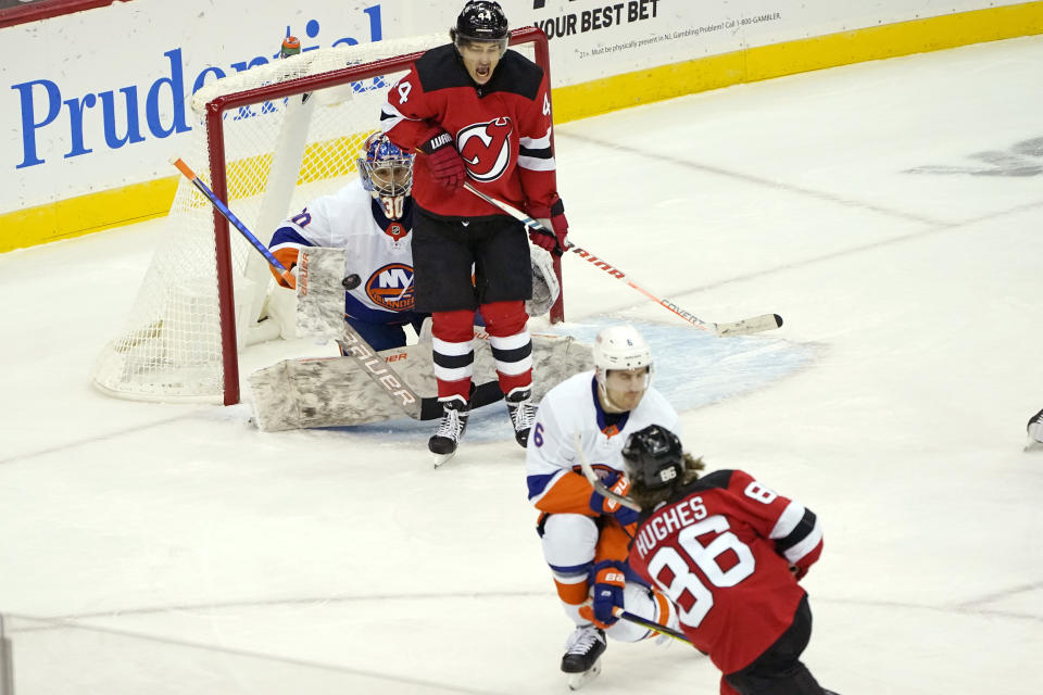 New Jersey Devils center Jack Hughes (86) shoots against New York Islanders goaltender Ilya Sorokin (30) and scores as Devils left wing Miles Wood (44) reacts with Islanders defenseman Ryan Pulock (6) defending during the first period of an NHL hockey game, Sunday, Jan. 24, 2021, in Newark, N.J. (AP Photo/Kathy Willens)