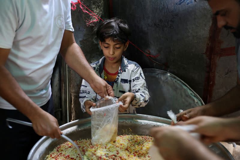 FILE PHOTO: Boy helps volunteers to prepare meals to be distributed at a charity kitchen during the holy month of Ramadan in Sanaa