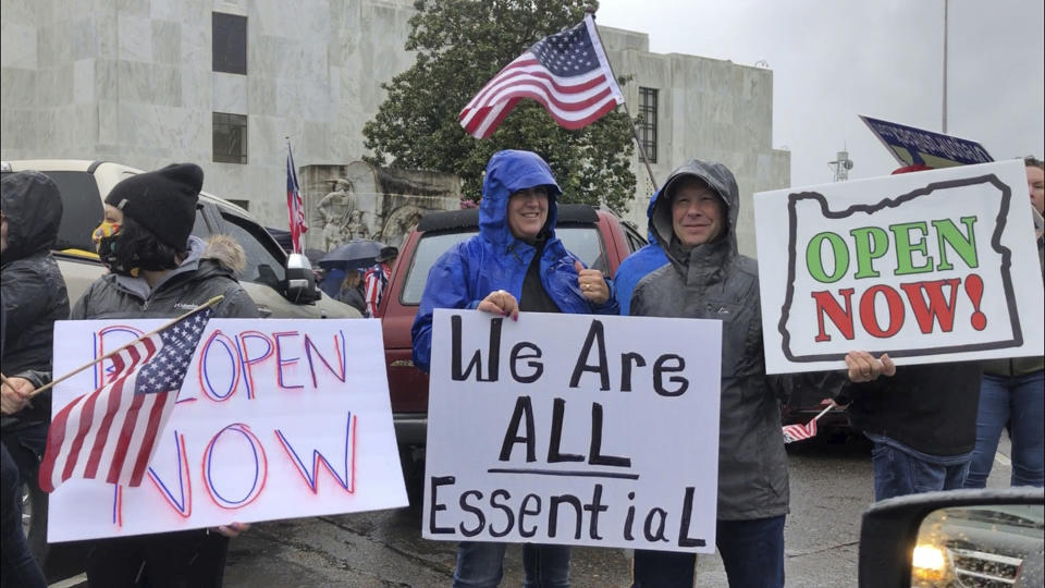 FILE - In this May 2, 2020, file photo, people hold signs protesting Oregon Gov. Kate Brown's executive order that shut down much of the state's economy and imposed social distancing, in her effort to stem the spread of the coronavirus, rally outside the Oregon State Capitol in Salem, Ore. A judge in rural Oregon on Monday, May 18, tossed out statewide coronavirus restrictions imposed by Brown, saying she didn’t seek the Legislature's approval to extend the stay-at-home orders beyond a 28-day limit. (AP Photo/Andrew Selsky, File)