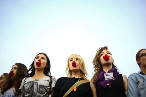 Women hold carnations in their mouth as a sign of protest during the Slut Walk