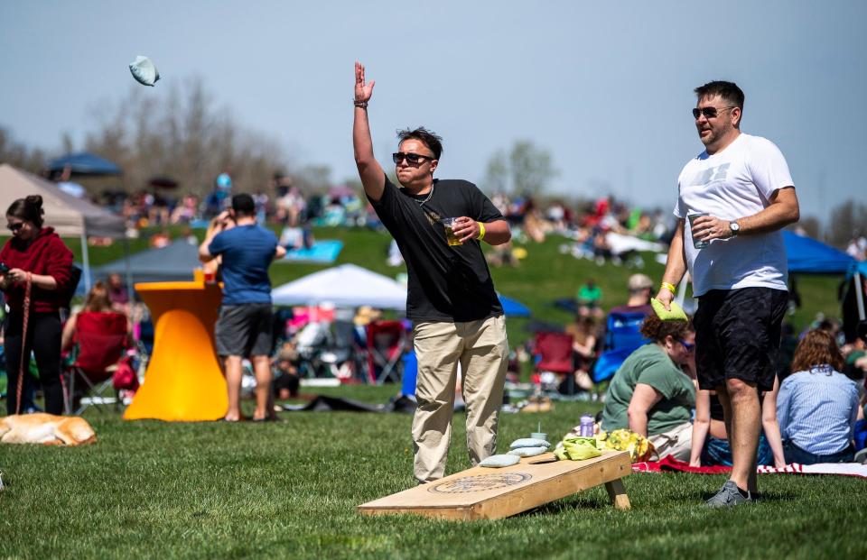 Nick Madrid, from Texas, tosses a cornhole bag as his teammate, Brandon Anderson, from Minnesota, right, watches at Switchyard Park on April 8, 2024.