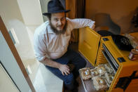 Eli Chitrik from Turkey shows bagel sandwiches at his hotel room in Doha, Qatar, Monday, Nov. 28, 2022. Stored into bright orange cases in Rabbi Eli Chitrik’s hotel room are bagels stuffed with vegetables. The labels declare the sandwiches kosher, or in compliance with Judaism’s set of dietary regulations. Freshly baked, they are made in Qatar at a designated kitchen, set up to feed Jewish World Cup visitors who want to keep kosher during the tournament. (AP Photo/Moises Castillo)