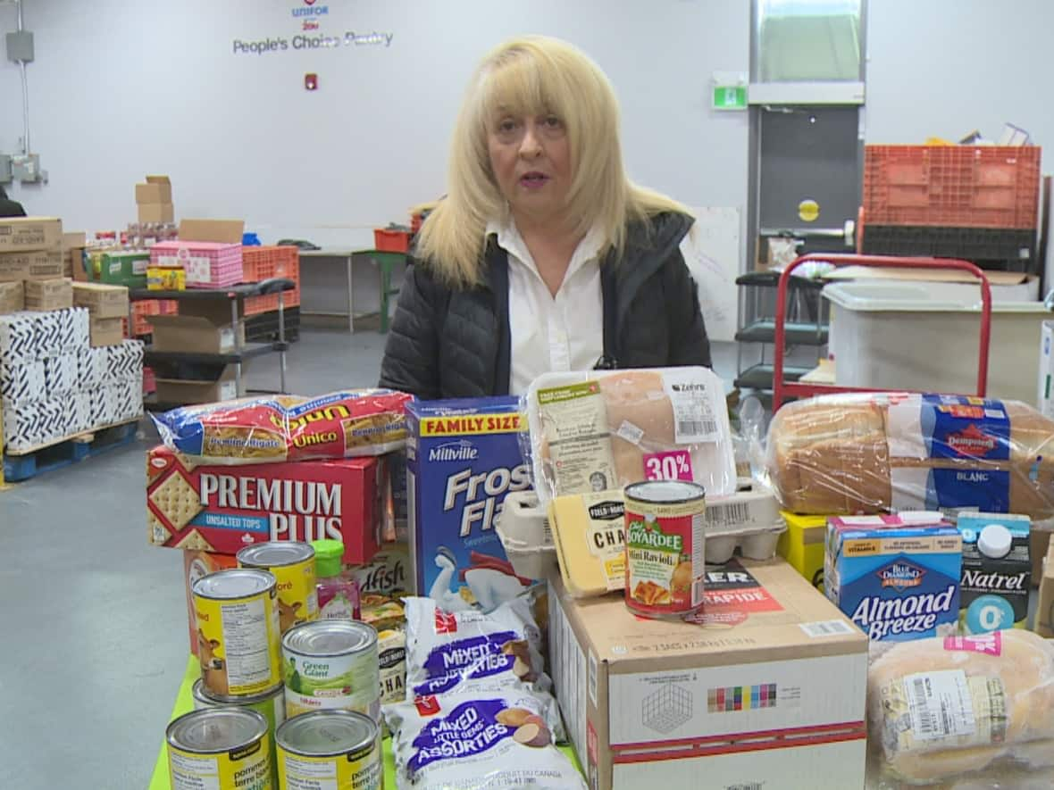 June Muir, president of the Windsor-Essex Food Bank Association, stands in front of about $200 worth of groceries, about the same amount the rebate could buy. (TJ Dhir/CBC - image credit)