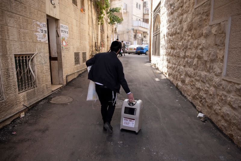 An ultra-Orthodox Jewish volunteer from Chasdei Amram, which provides home relief to people affected by the coronavirus coronavirus disease (COVID-19), carries a home oxygen concentrator as he makes his way in Jerusalem