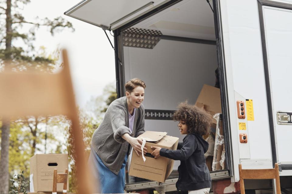 side view of boy helping mother in unloading cardboard box from van