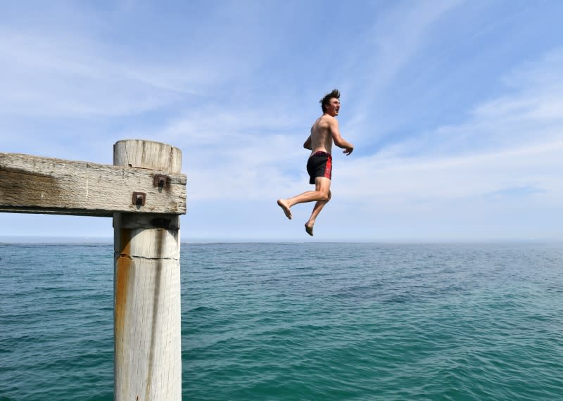 A swimmer jumps from the Port Noarlunga Jetty in Adelaide