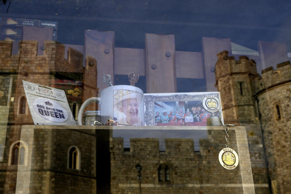 Windsor Castle is reflected in the window of a shop selling Royal souvenirs outside the Castle, in Windsor, England, Friday, Oct. 22, 2021. Britain's Queen Elizabeth II spent a night in a hospital for checks this week after canceling an official trip to Northern Ireland on medical advice, Buckingham Palace said Thursday. The palace said the 95-year-old British monarch went to the private King Edward VII's Hospital in London on Wednesday for "preliminary investigations." It said she returned to her Windsor Castle home at lunchtime on Thursday, "and remains in good spirits."(AP Photo/Kirsty Wigglesworth)