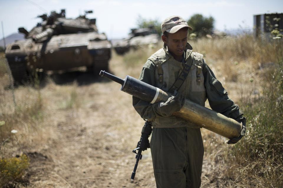 An Israeli soldier carries a tank shell near Alonei Habashan on the Israeli occupied Golan Heights, close to the ceasefire line between Israel and Syria June 22, 2014. A(REUTERS/Baz Ratner)